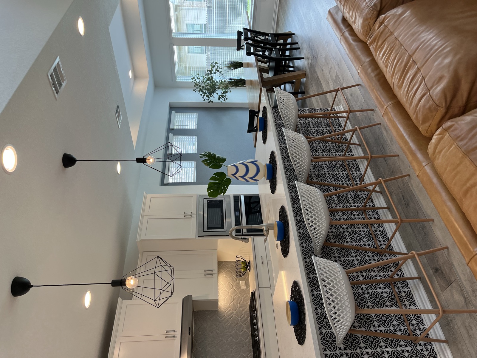 Open kitchen and dining space staged by Black Oak Decor with a patterned island, woven counter stools, and blue accents
