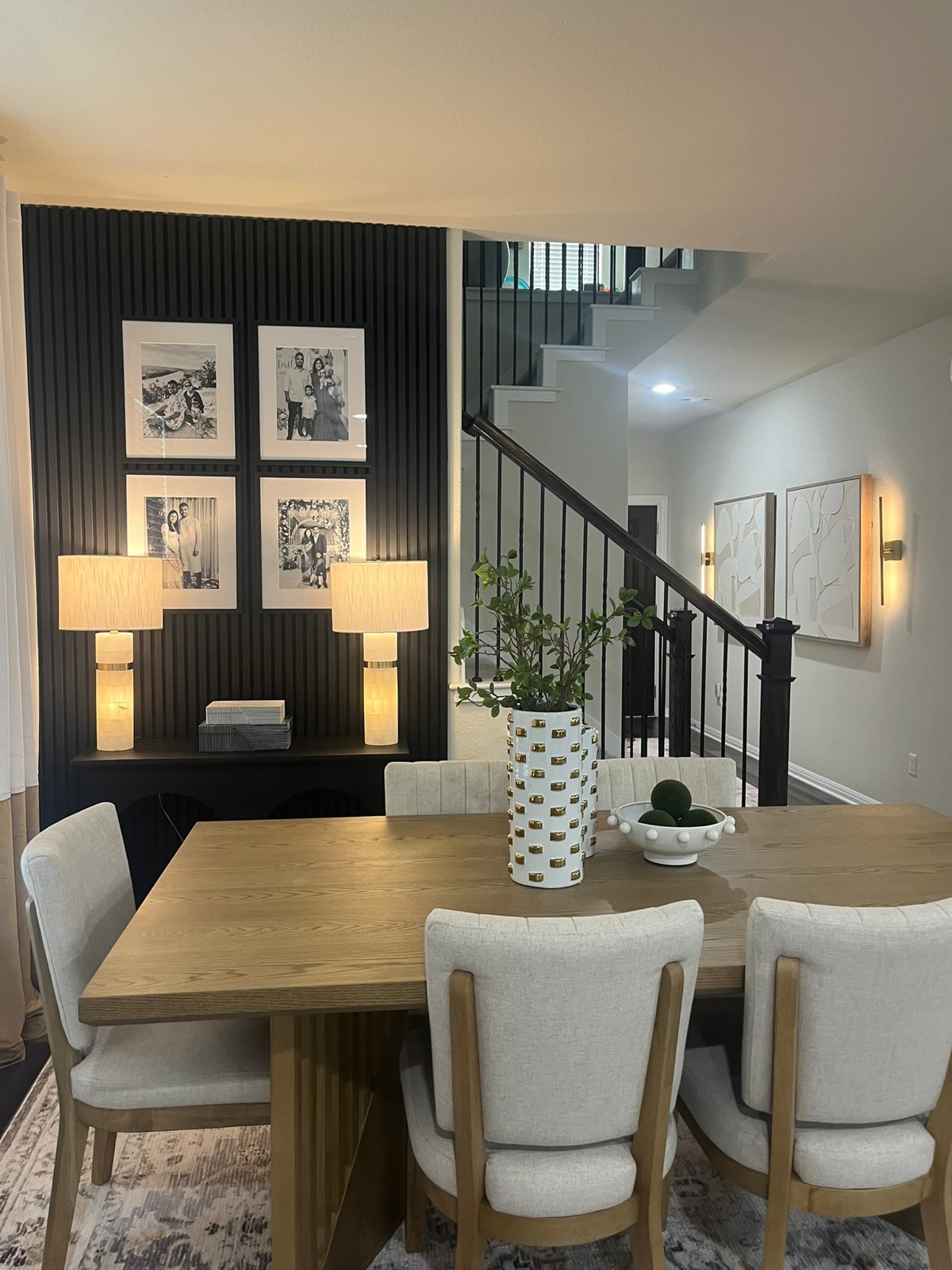 Dining room designed by Black Oak Decor with black slat accent wall and oak table